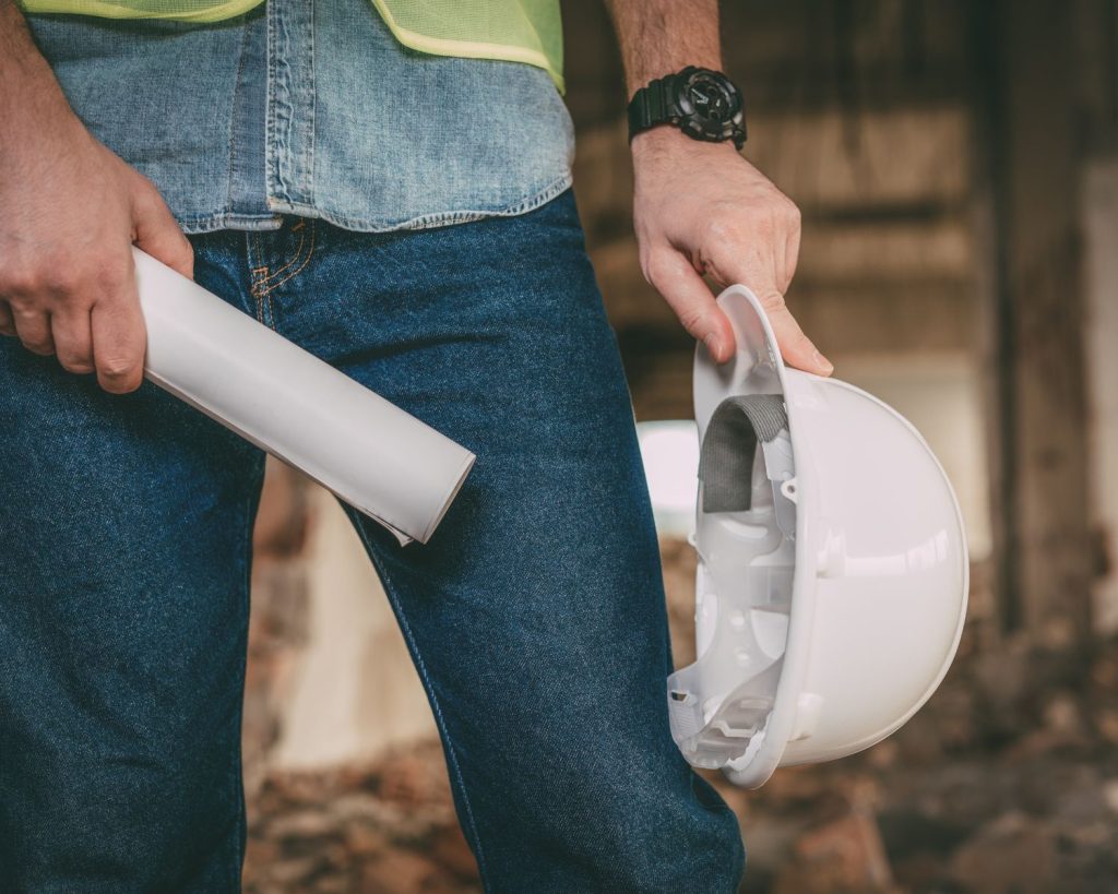 Homme tenant un casque de chantier et un plan