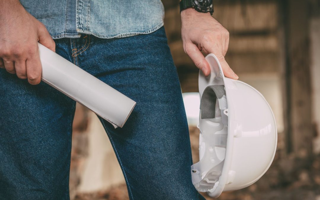 Homme tenant un casque de chantier et un plan