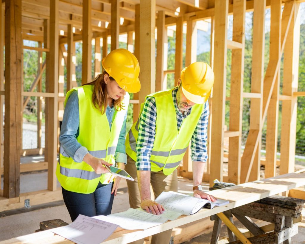 Deux ingénieurs qui regardent les plans du bâtiments en construction dans lequel ils se trouvent.