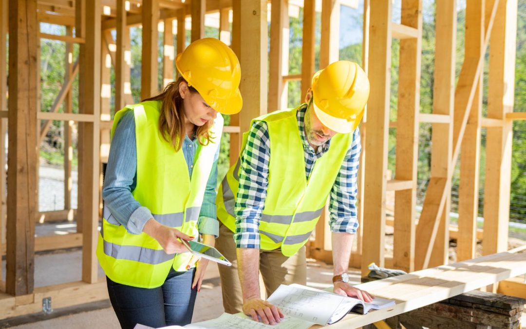 Deux ingénieurs qui regardent les plans du bâtiments en construction dans lequel ils se trouvent.